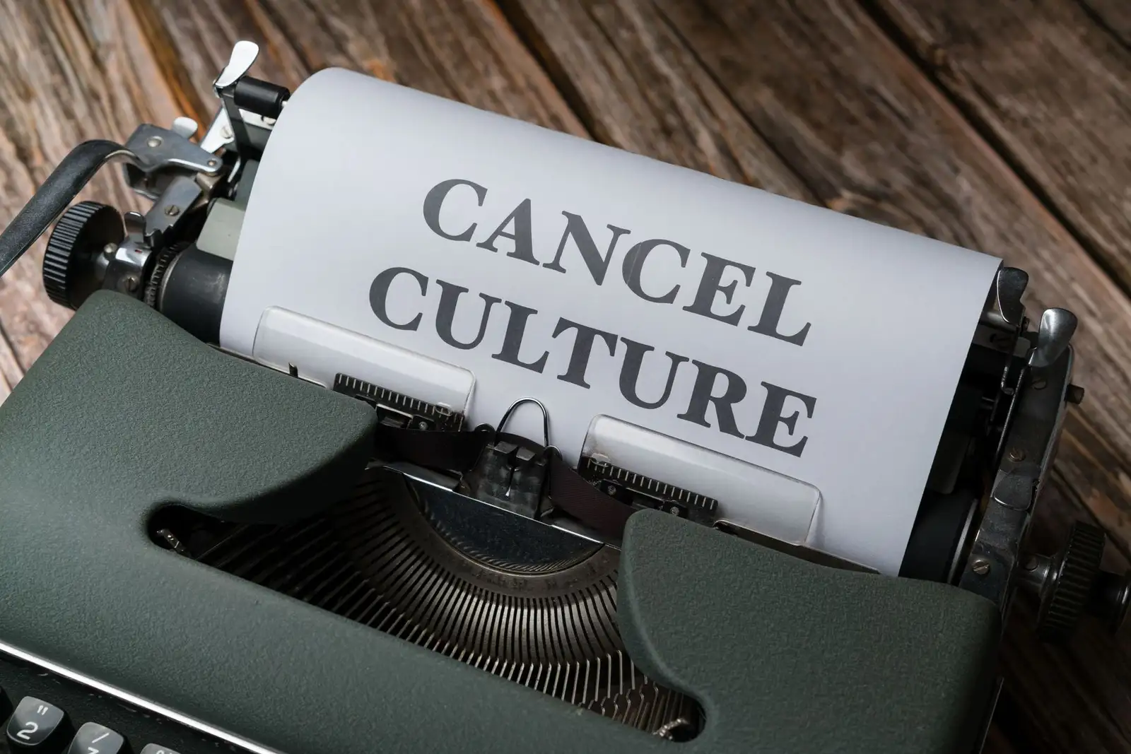 Vintage typewriter with paper reading 'Cancel Culture' on wooden surface.